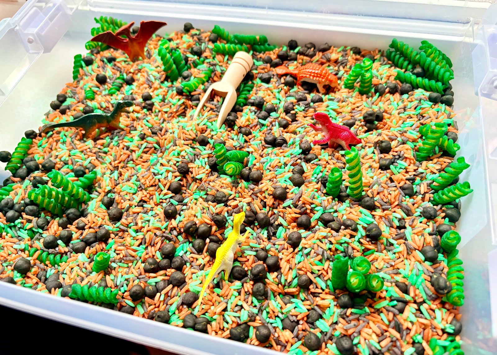 Close-up of colourful dinosaur-themed sensory filler and dinosaur play pieces